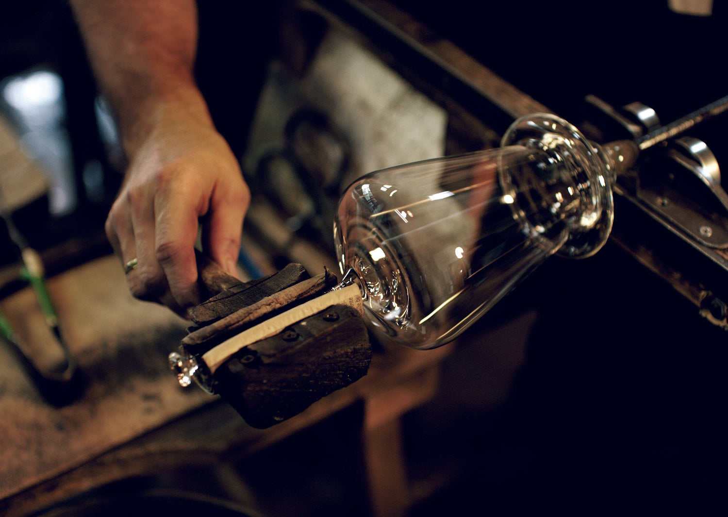 Glassblowing process with a glass tube being shaped by a hand.