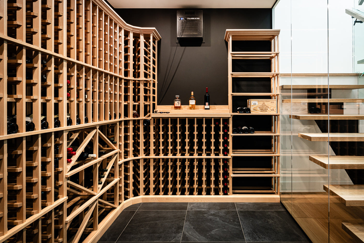 Modern wine cellar with wooden racks and a staircase in the background