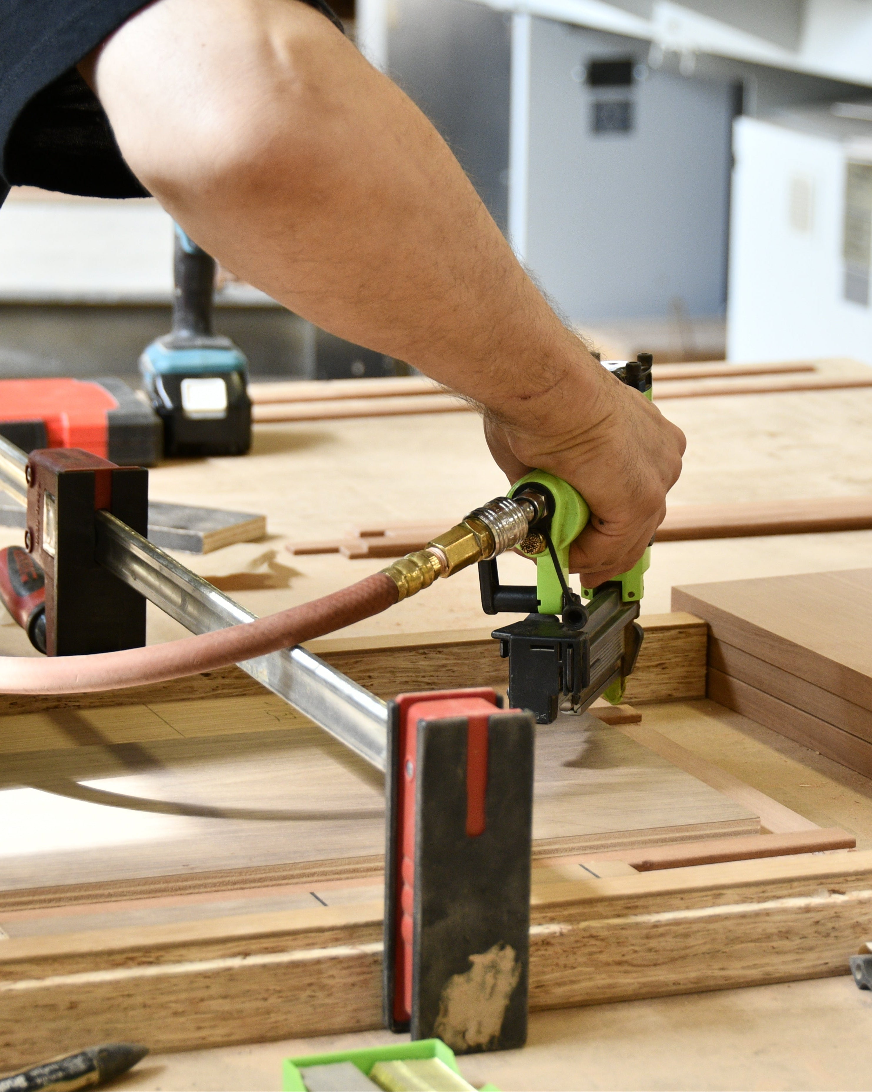 Person using a power tool on a wooden workbench in a workshop.