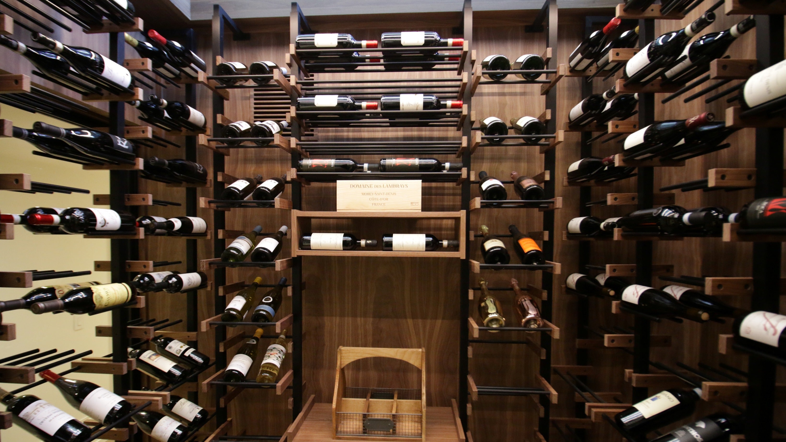 Wooden wine cellar with rows of wine bottles and a chair in the center.