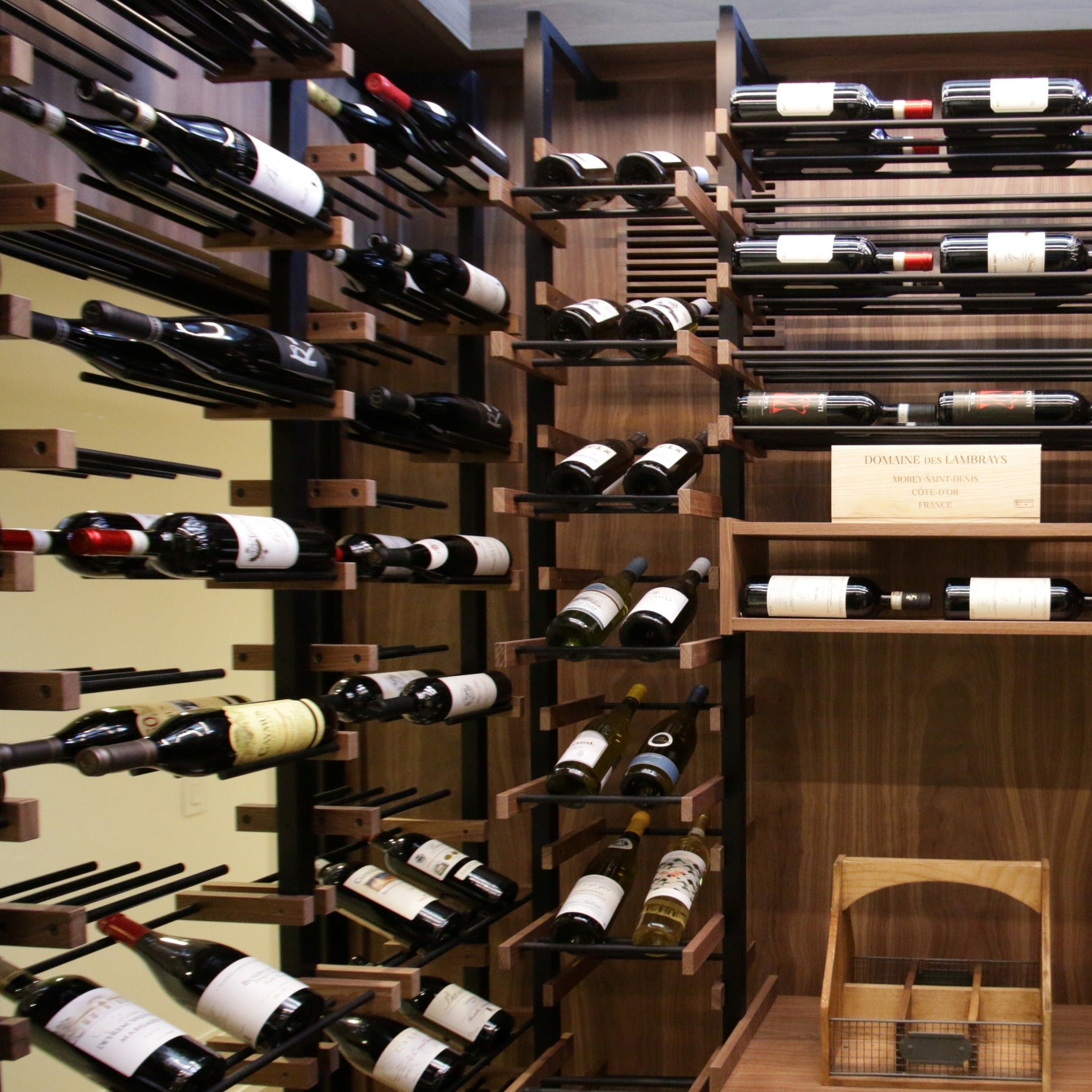 Wooden wine rack with neatly arranged bottles in a home wine cellar.