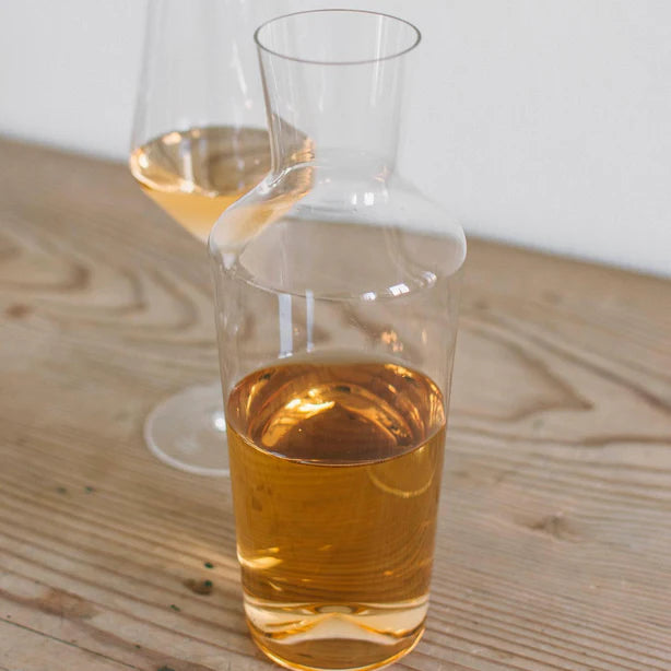 Clear glass carafe and glass filled with amber liquid on a wooden surface