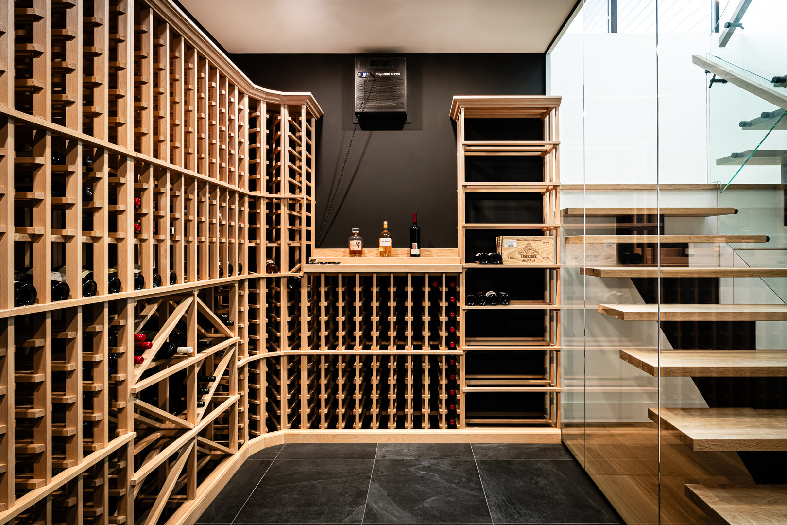 Modern wine cellar with wooden racks and a staircase in the background