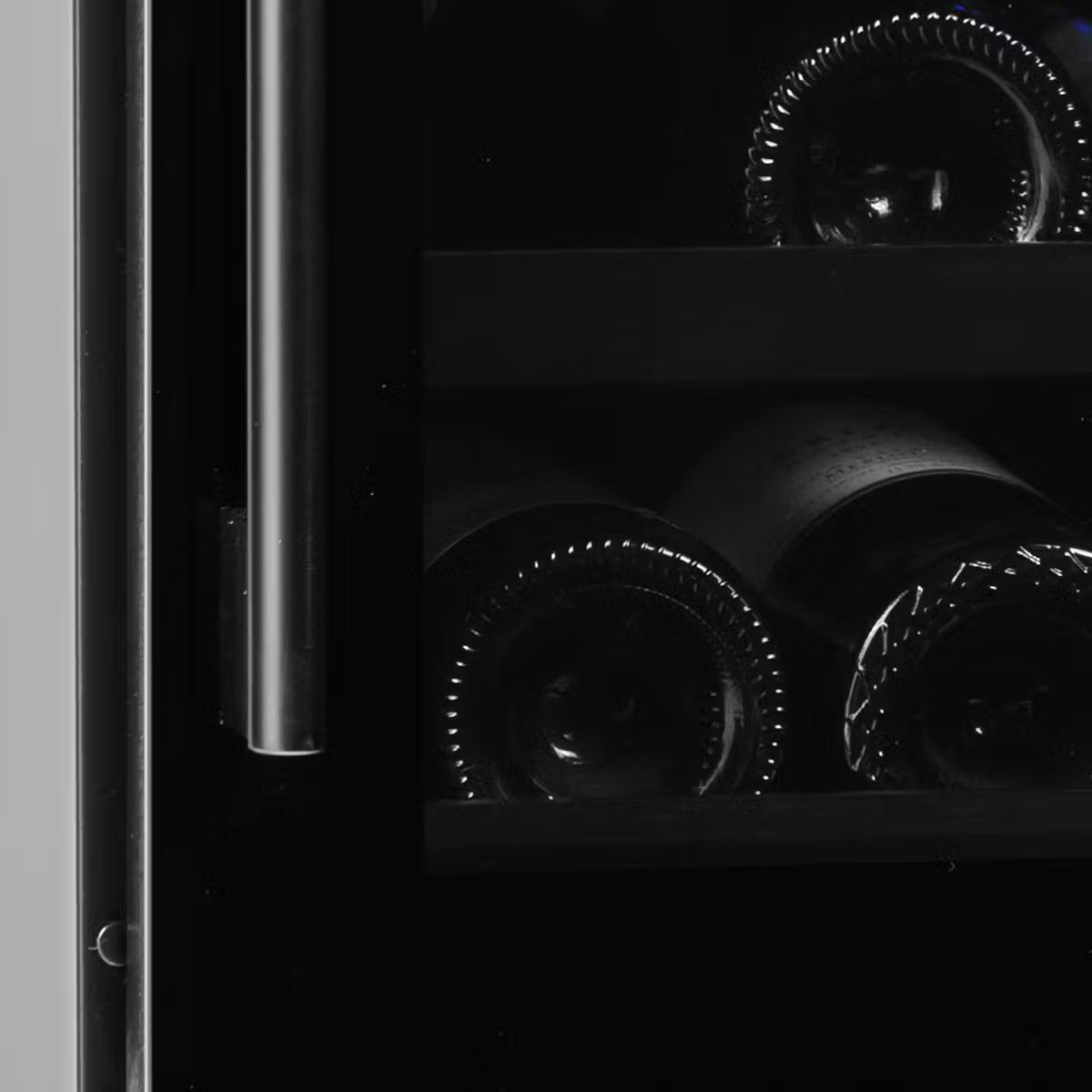 Wine bottles in a dark setting, possibly inside a wine cooler.